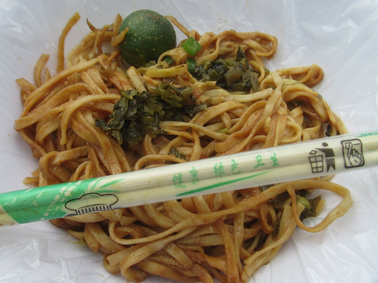 Chopsticks resting on a plate of noodles
