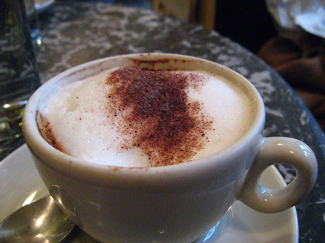 A cup of coffee with thick milk foam dusted with cocoa
