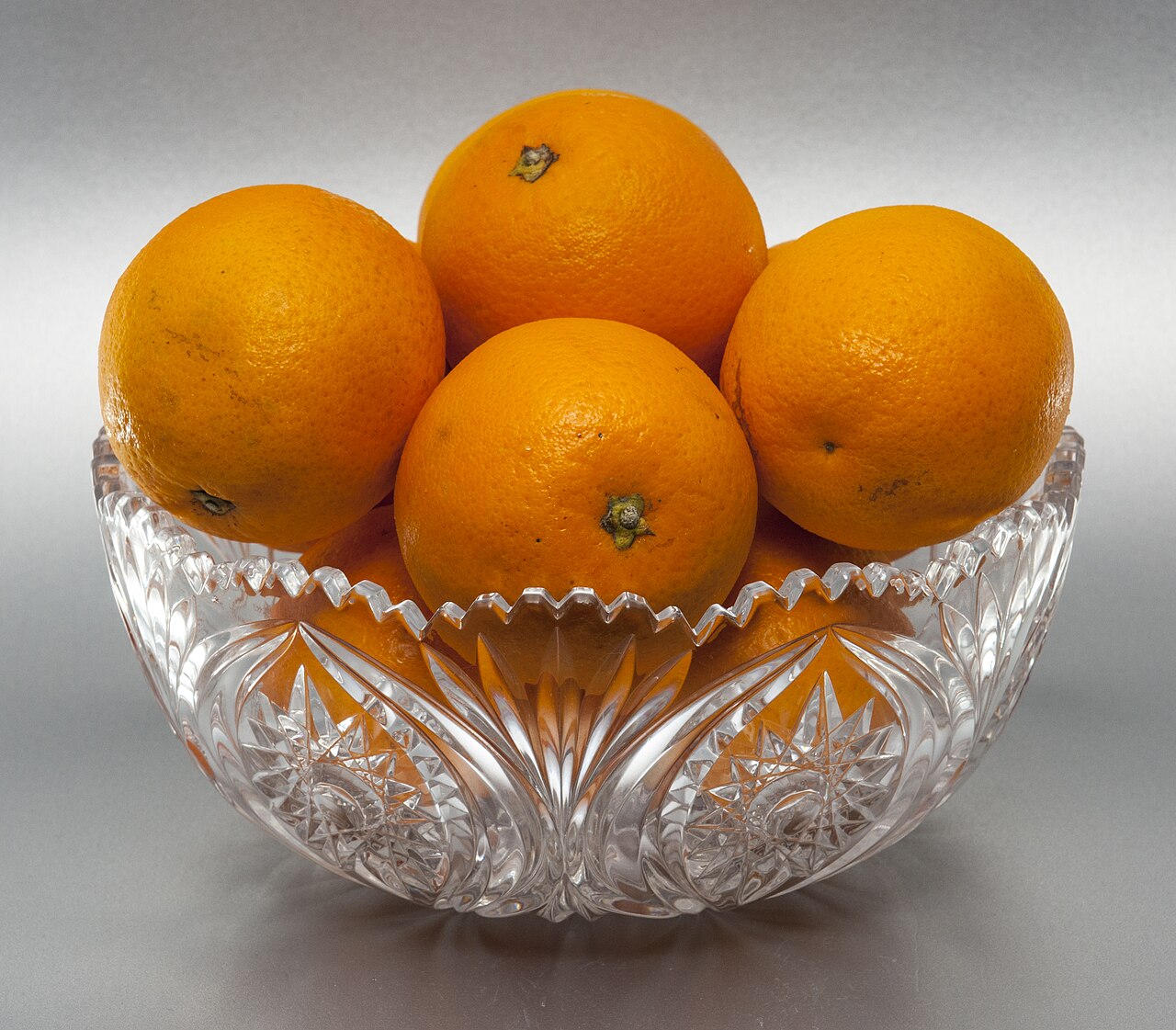 Oranges in a glass bowl on a white background