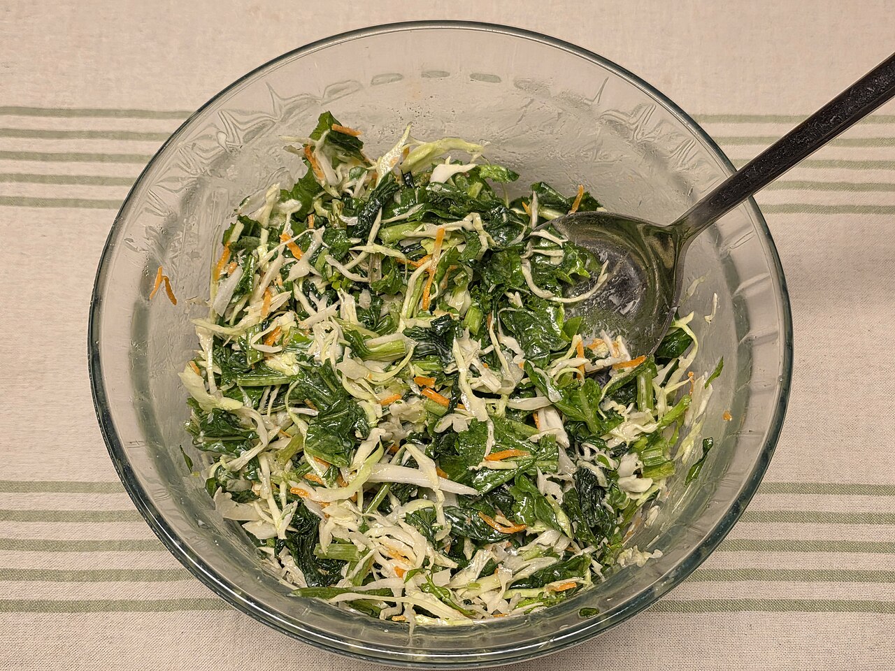 A bowl of salad with green leaves and dressing