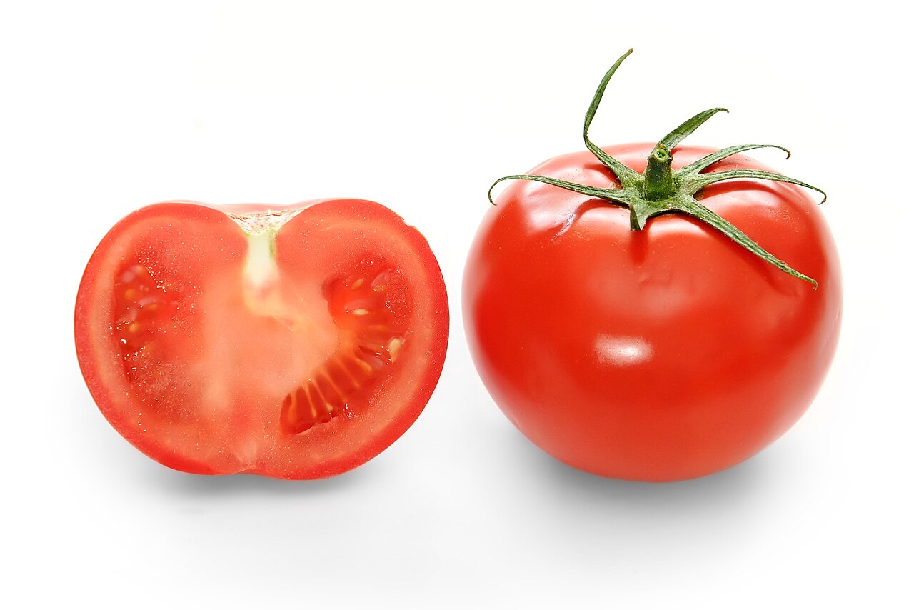 A red tomato and a cut half tomato on white